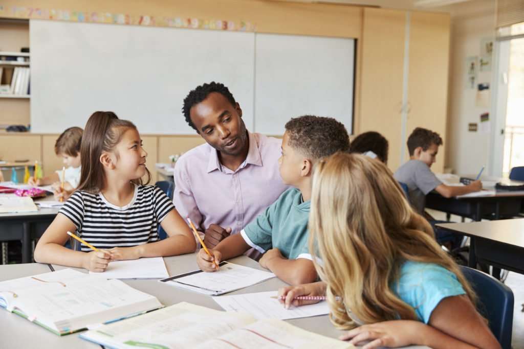Teacher working with elementary school kids at their desk