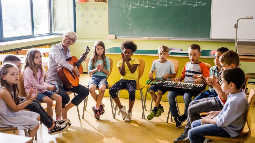teacher playing the guitar in a musical education class